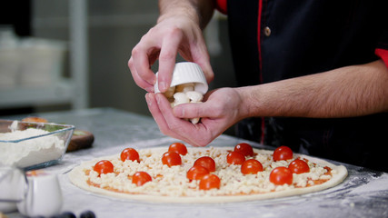 Obraz na płótnie Canvas Restaurant kitchen. A chef putting special cheese on the pizza