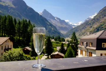 Fotobehang Champagne glass on mountain village background © Steven