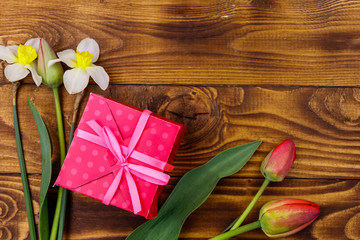 Gift box and bouquet of red tulips and daffodils on wooden background. Concept of Valentine's Day, Women's Day, Mother's Day and Birthday. Top view, copy space
