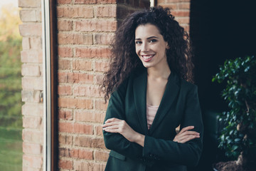 Portrait cute millennial charming freelancer content glad rejoice satisfied enjoy excited relaxed long wavy curly hair hairstyle stand window interior dressed modern stylish trendy classic jacket