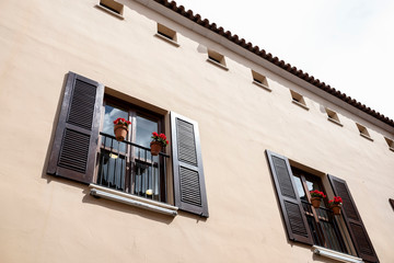 wall facade with two wooden balconies and pots with red flowers