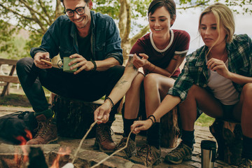 Friends toasting food on bonfire in the countryside