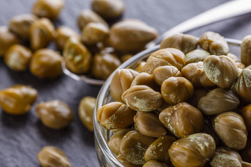 pickled capers on a dark stone background