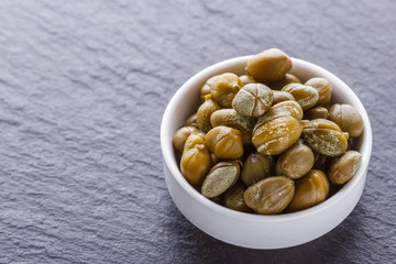 pickled capers on a dark stone background