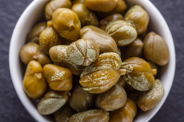 pickled capers on a dark stone background