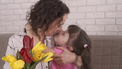 Portrait of a happy mother with daughter. Happy woman with a bouquet of tulips hugs her little daughter. Mothers Day. - Powered by Adobe
