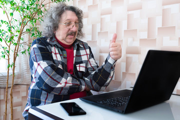 A portrait of an elderly man using a laptop. The meaning of lifestyle.