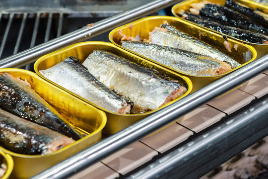 Tin cans with fish on the conveyor.