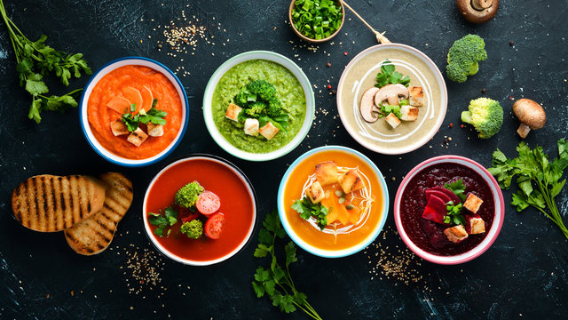 Assortment Of Colored Vegetable Cream Soups. Dietary Food. On A Black Stone Background. Top View. Free Copy Space.