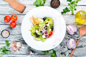 Greek salad. Vegetable salad with feta cheese, olives and cherry tomatoes. In the plate. Top view. Free space for your text. Rustic style.