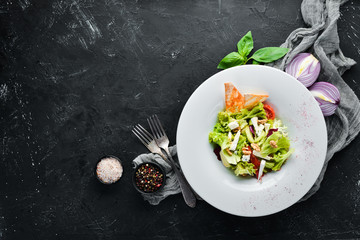 Vegetable salad with cheese, olives and cherry tomatoes. In the plate. Top view. Free space for your text. Rustic style.