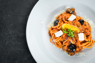 Spaghetti with tomatoes, olives and feta cheese in a plate. Top view. Free space for your text.