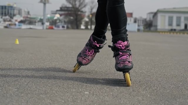Close up of legs rides on roller skates and whirl in slow motion. Girl driving roller skates.