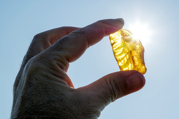 male hand holds amber against the sun