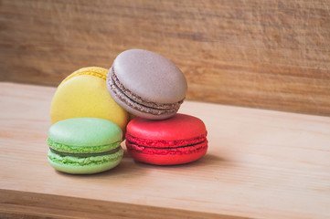 Colorful tasty french macarons isolated on wood texture