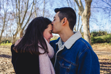 Happy young couple smiling together in a sunny forest on an autumn day.