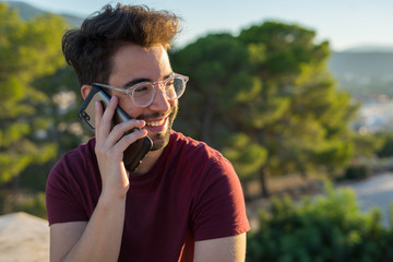 Young man talking on the mobile phone in the countryside