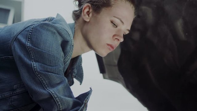 Low angle of a woman checking her vehicle fluid levels under the hood at home, 60 fps.