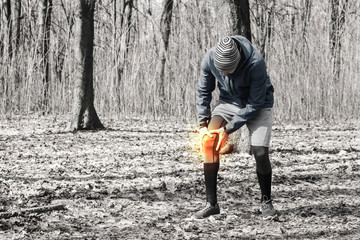 A man in training clothes got a knee injury while jogging in outdoor workout. Concept of sports...