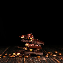 Scattered coffee grains and black chocolate on a wooden table.