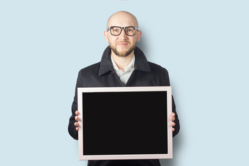 A man holds a board in his hands on a light background. Copy space.
