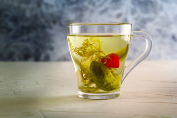 Glass with cucumber pickle stands on a wooden table. Copy space