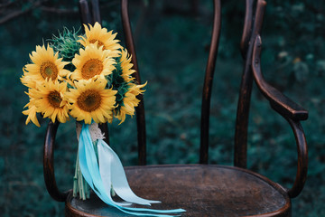 Bright sunflower bouquet, yellow bridal hand-tied baby's breath bouquet on wooden chair in nature