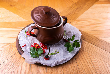 Closed clay pan with food on wooden table.