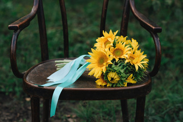 Bright sunflower bouquet, yellow bridal hand-tied baby's breath bouquet on wooden chair in nature
