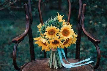 Bright sunflower bouquet, yellow bridal hand-tied baby's breath bouquet on wooden chair in nature