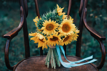 Bright sunflower bouquet, yellow bridal hand-tied baby's breath bouquet on wooden chair in nature
