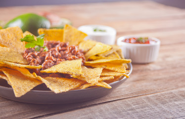 Mexican corn chips nachos with salsa and sour cream dips