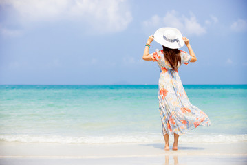 Happy traveler asia woman in dress with sun hat standing on beach  enjoys her tropical  vacation ,...