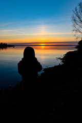 siluette of a young person standing infront of a sunrise