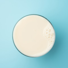 Cup glass with milk or soya soy bean bubble foam on top view isolated t on blue background food...