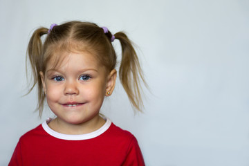 Portrait of  little girl with blue eyes biting lower lip looking at camera on  the white background