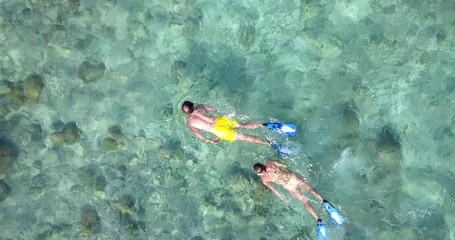 Man and woman swimming through crystal clear water in tropical paradise. Top down view 4k