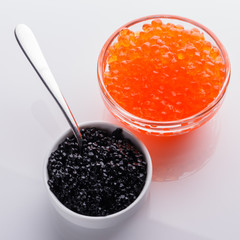 red and black caviar in a bowl on a white acrylic background
