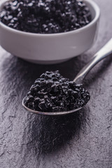 black caviar in a bowl on a dark stone background
