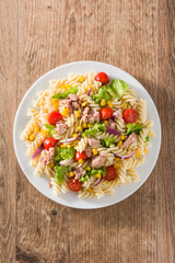 Pasta salad with vegetables and tuna on wooden table. Top view