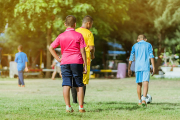 Obraz premium Asian boys practice kicking the ball to score goals in the public football field.