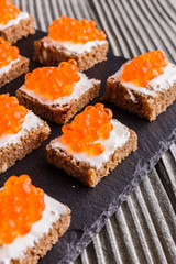 Snack with red and black caviar on a stone plate