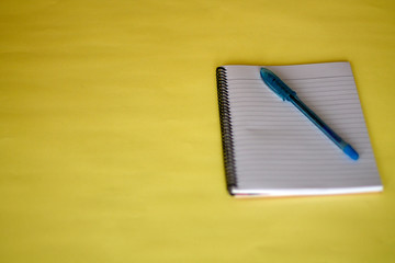 Notebooks, pens and glasses placed on a yellow background, the view of work