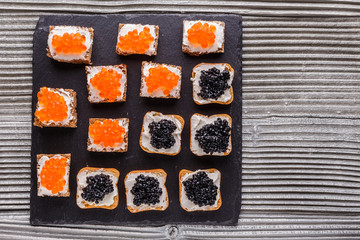 Snack with red and black caviar on a stone plate
