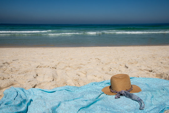hat and canga on the beach sand with the sea in the background