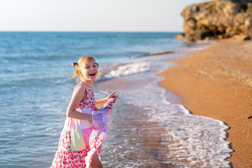 Happy child running and jumping in the waves during summer vacation on exotic tropical beach. Holiday on ocean coast for family with young children. Kids play at the sea