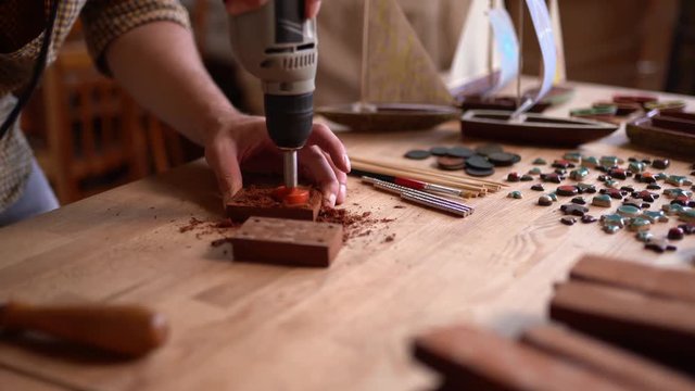 Carpenter uses a drill rotary tool o carve wooden plank