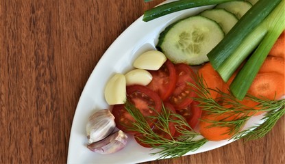 vegetables on a plate, carrots, tomatoes, cucumbers, dill and garlic