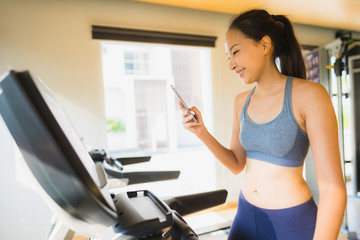 Portrait beautiful asian young woman using mobile phone in gym