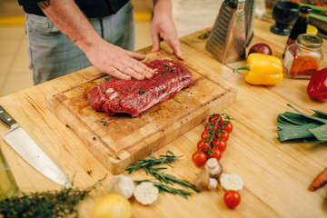 Male person hands seasoning piece of raw meat